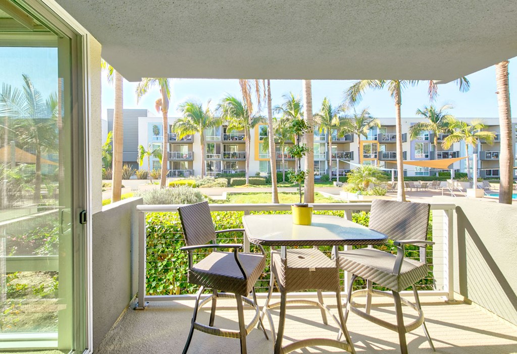 a patio with a table and chairs on a balcony with palm trees