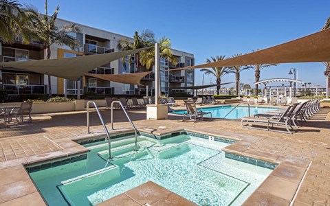 a resort style pool with chairs and umbrellas next to a building