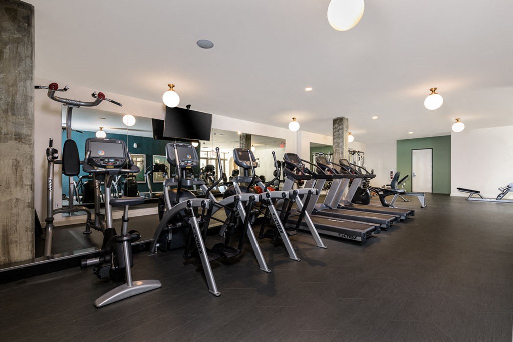 a gym with various cardio machines and weights