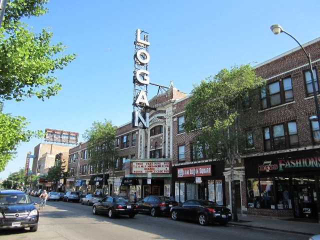 a city street with cars parked in front of a theater sign