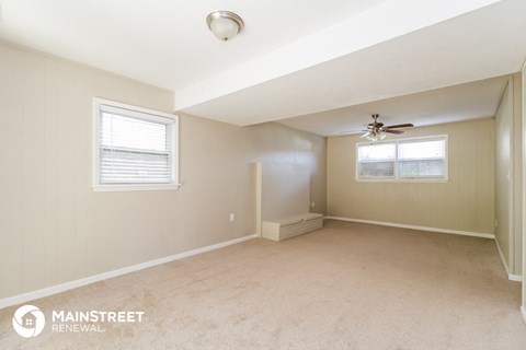 an empty room with a ceiling fan and two windows