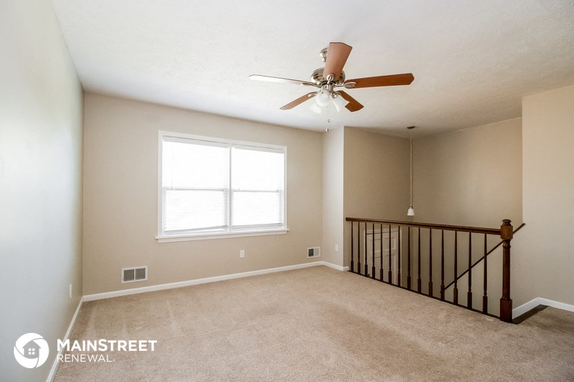 the upstairs loft has a ceiling fan and a window