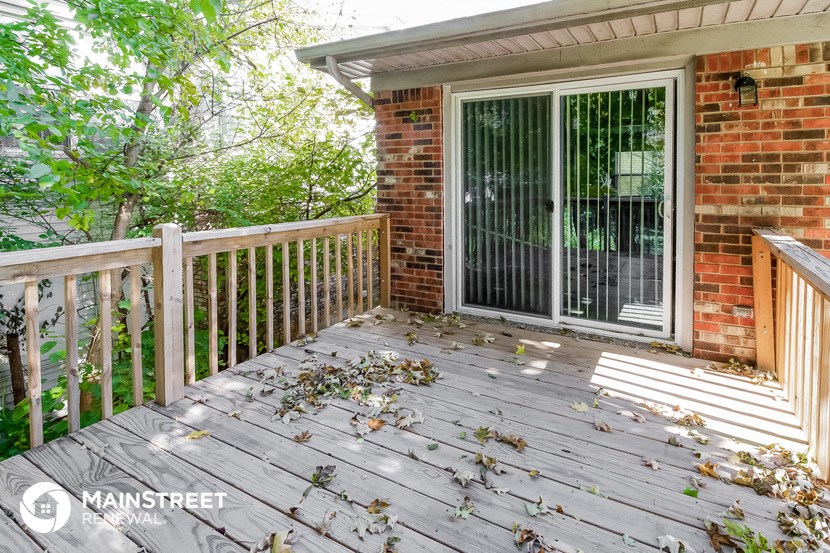 a backyard deck with a brick wall and a sliding glass door