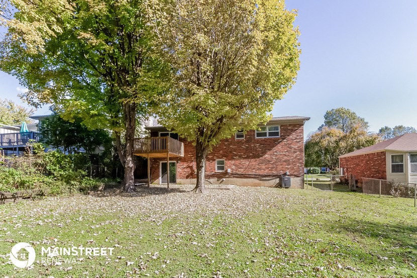 a house with a yard and trees in front of it