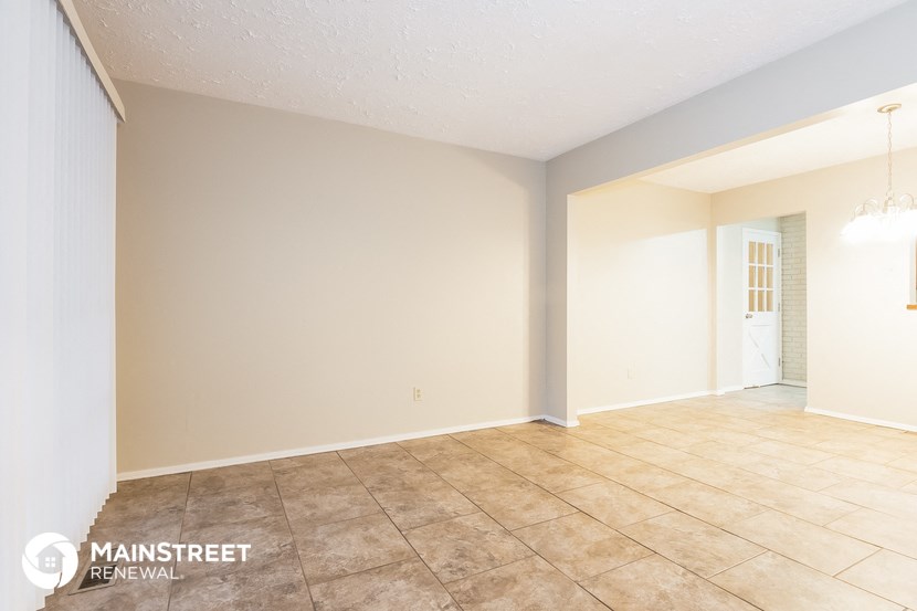 the spacious living room with tile flooring and white walls