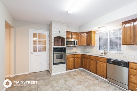 a kitchen with wooden cabinets and stainless steel appliances and a white door