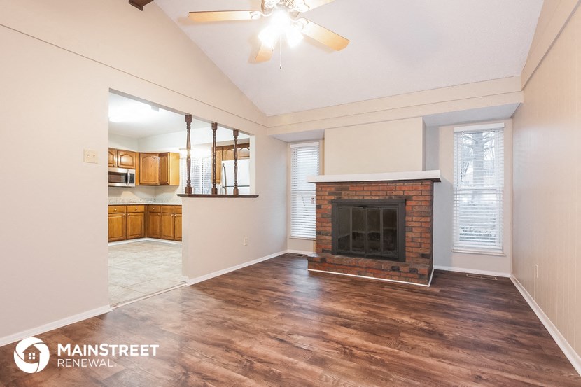 a living room with a brick fireplace and a ceiling fan