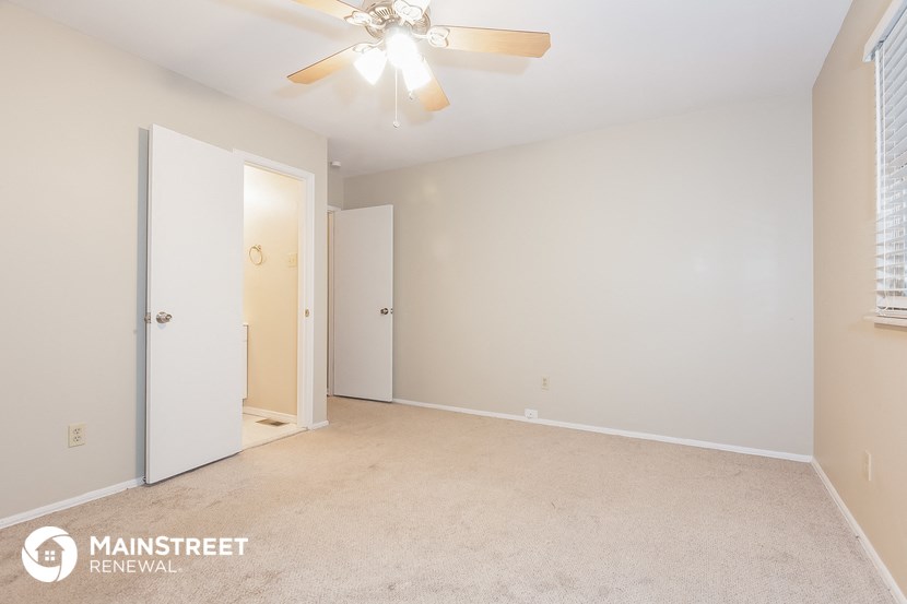 a bedroom with white walls and a ceiling fan