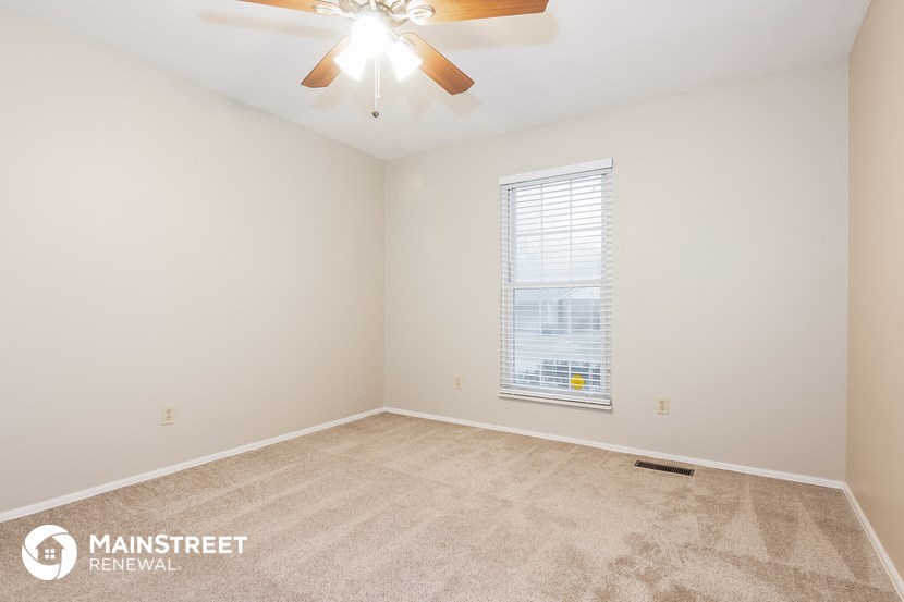 the spacious living room with carpeting and a ceiling fan
