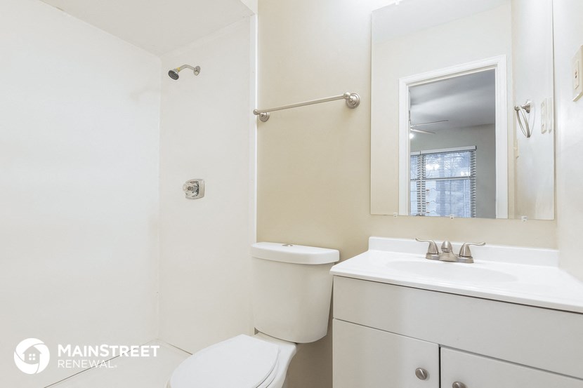 a white bathroom with a white toilet and a sink and a mirror