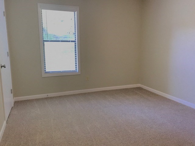 an empty room with a window and a carpet