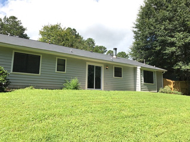 a blue house on a hill with a grass yard