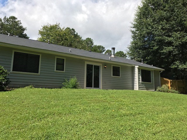 a blue house on a hill with a grass yard
