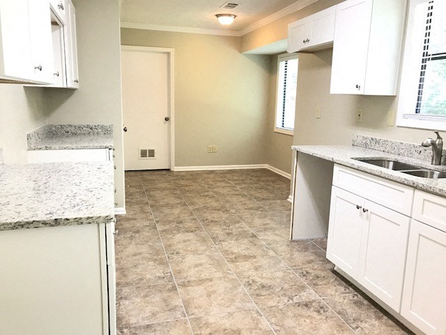 an empty kitchen with white cabinets and a sink