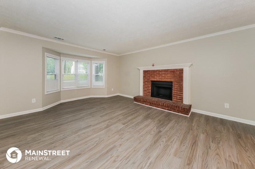 the living room of a house with a fireplace and wooden floors