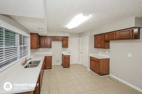 a kitchen with wooden cabinets and white counter tops and a sink