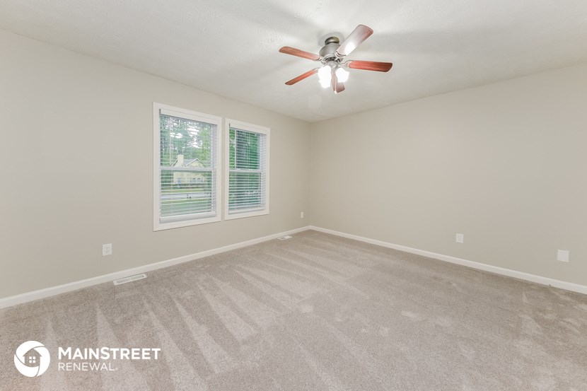 the spacious living room with carpeting and a ceiling fan