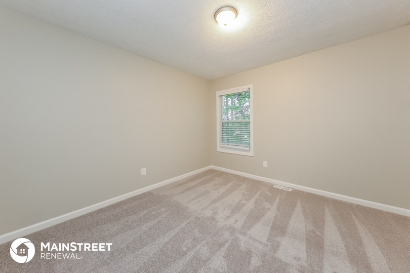 the spacious living room with carpeting and a window