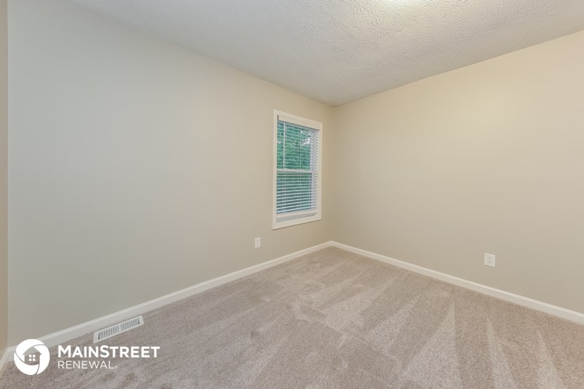 the upstairs bedroom has a carpeted floor and a window