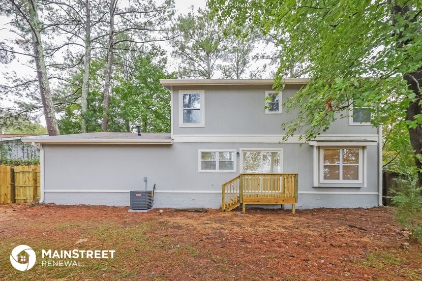 a small gray house with a wooden bench in front of it