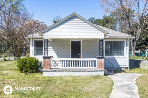 a small white house with a porch and a sidewalk