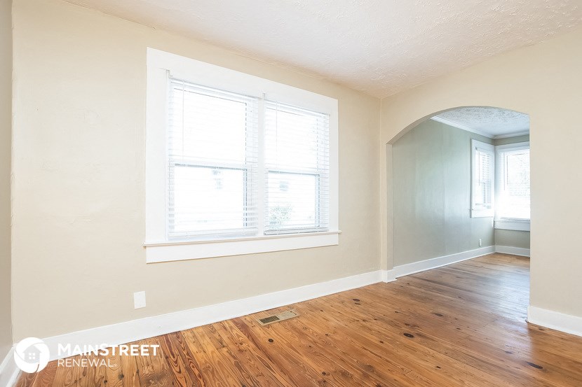 a living room with a hard wood floor and two windows