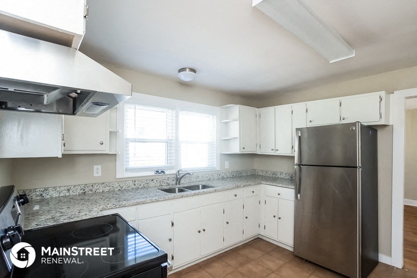 a kitchen with white cabinets and a stainless steel refrigerator