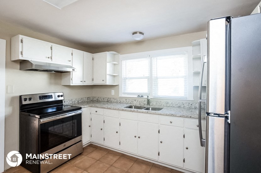 a kitchen with white cabinets and a black stove and refrigerator