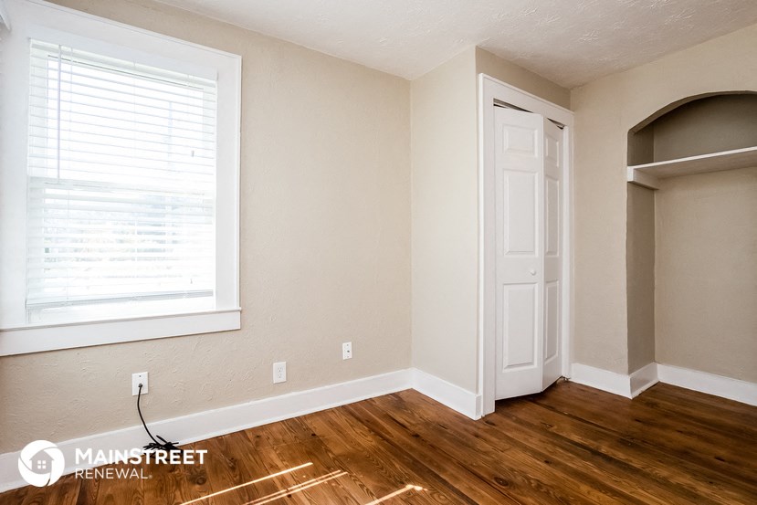 the living room of a home with wooden floors and a white door and a window