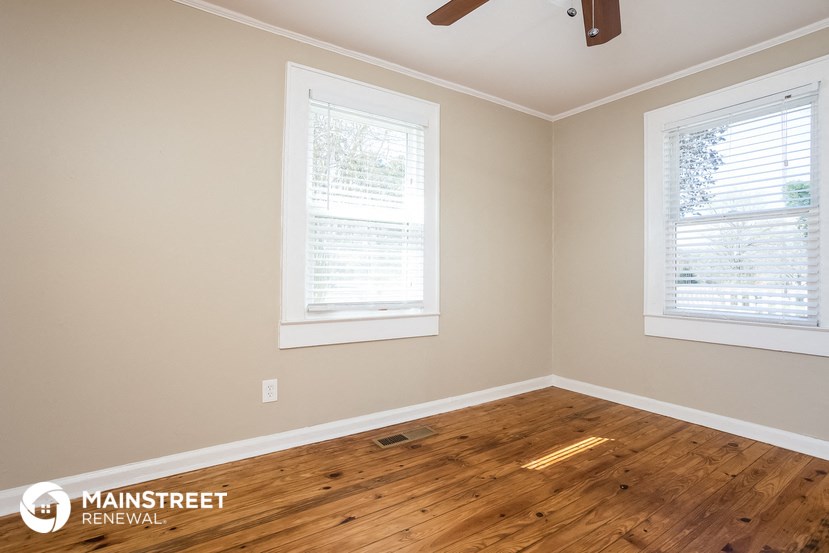 the living room of a home with a hardwood floor and two windows
