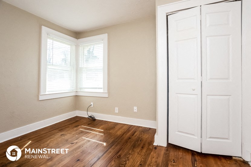 the living room of a home with white doors and wood floors