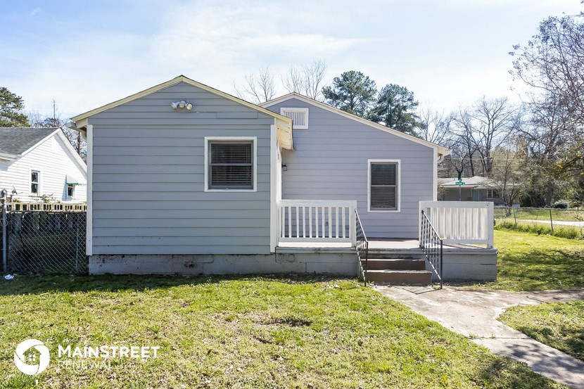a blue house with a porch and a white fence