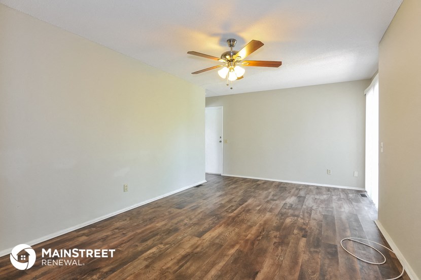 the living room and dining room of an empty house with a ceiling fan