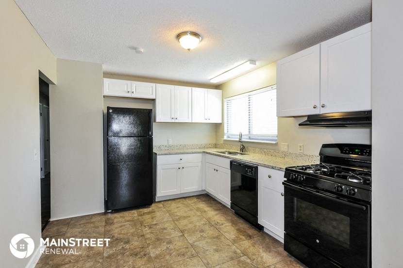 an empty kitchen with black appliances and white cabinets