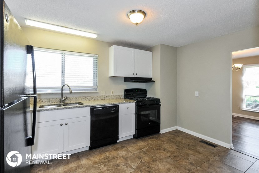 a kitchen with white cabinets and a black stove and a sink
