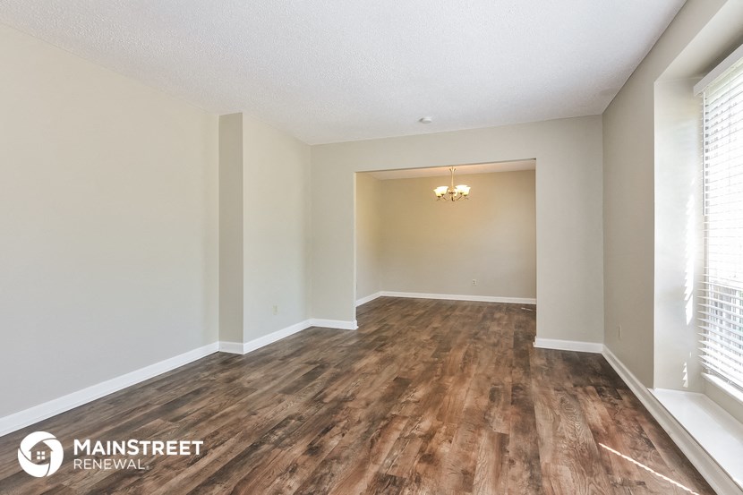 the spacious living room with wood flooring and white walls