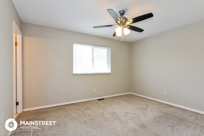 the master bedroom has a carpeted floor and a ceiling fan