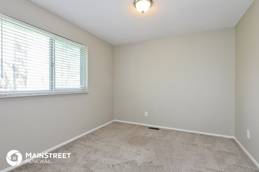 the spacious living room with a large window and carpeted flooring