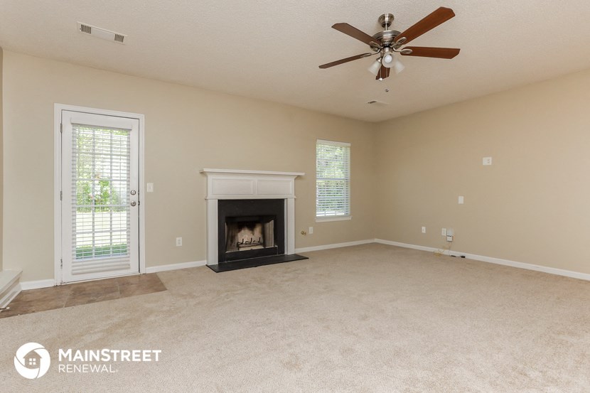 a living room with a fireplace and a ceiling fan