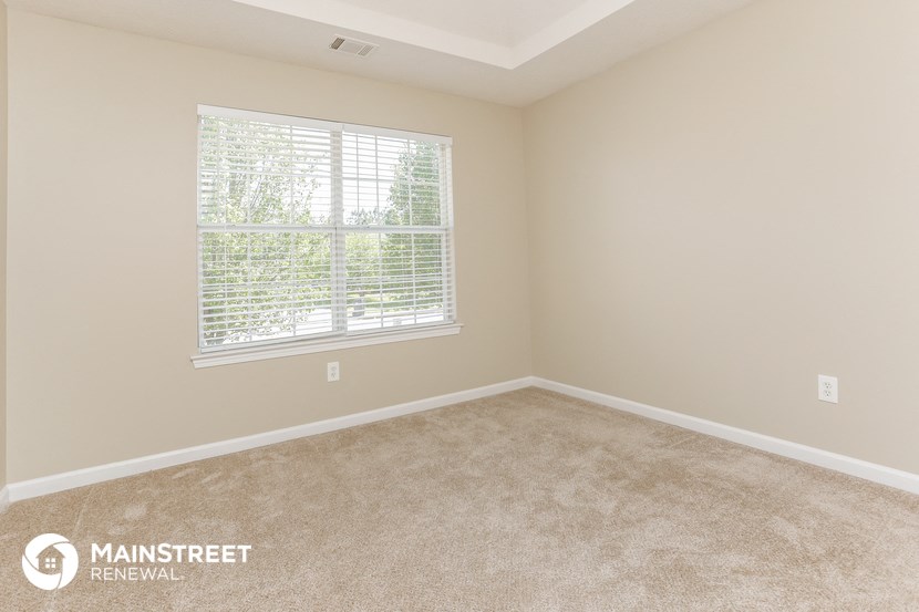 a bedroom with a large window and a carpeted floor