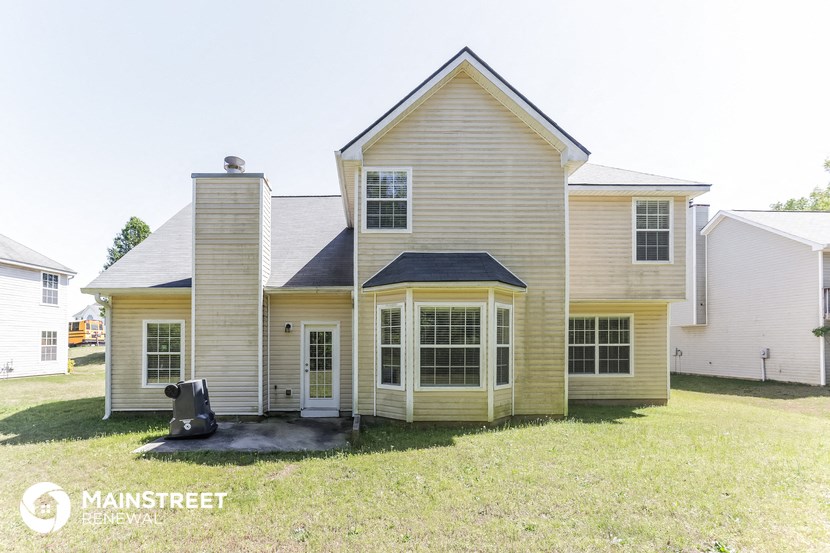 the front of a house with a black teddy bear in the yard