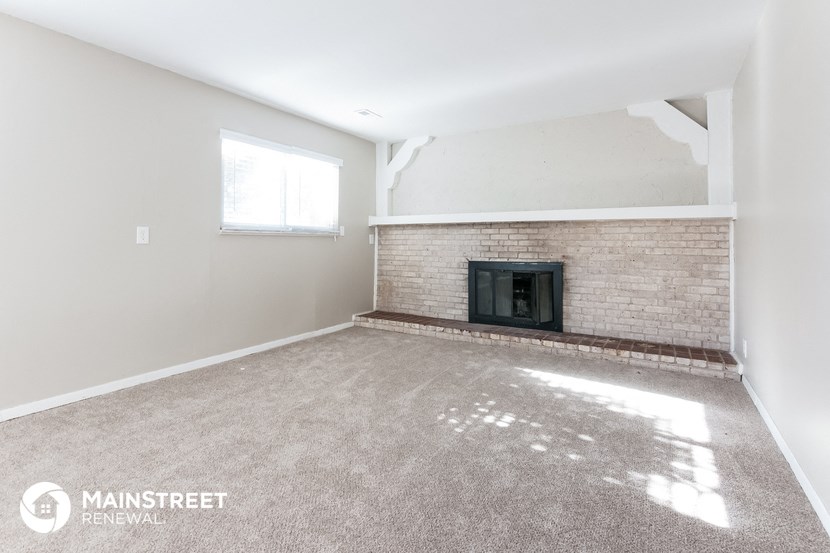 an empty living room with a fireplace and a window