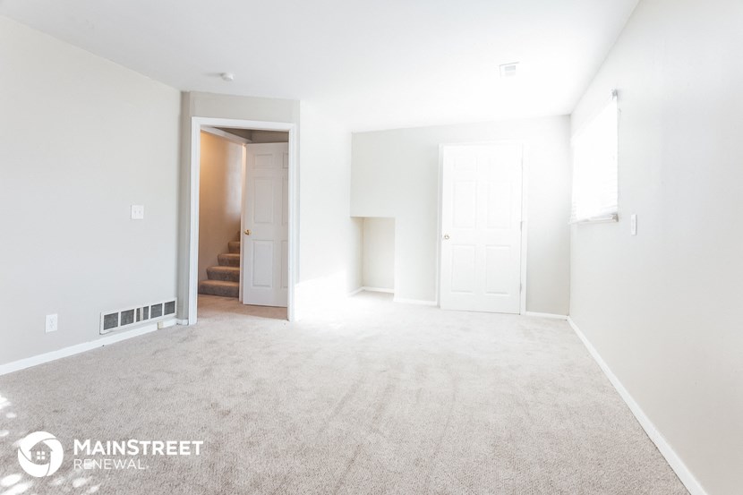 an empty living room with white walls and carpet