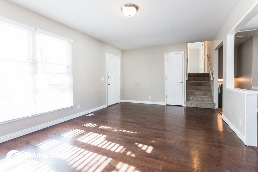 an empty living room with wood floors and a staircase