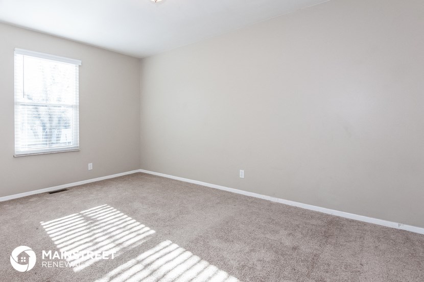 an empty room with a window and carpet