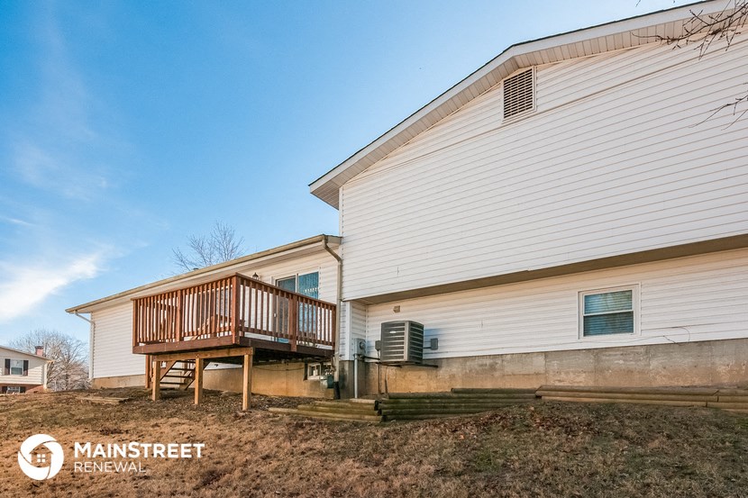 the back of a white house with a wooden deck and a porch
