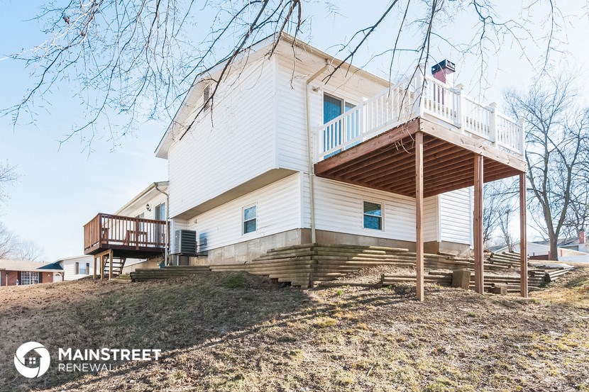 a white house with a deck on a hill