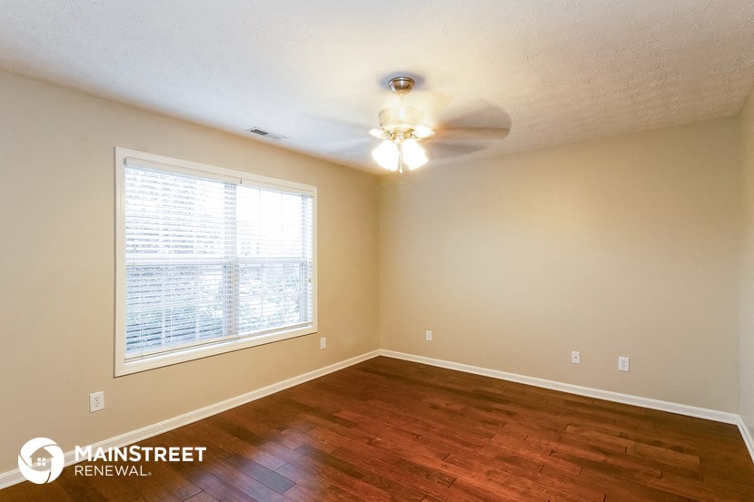 the spacious living room with wood flooring and a ceiling fan