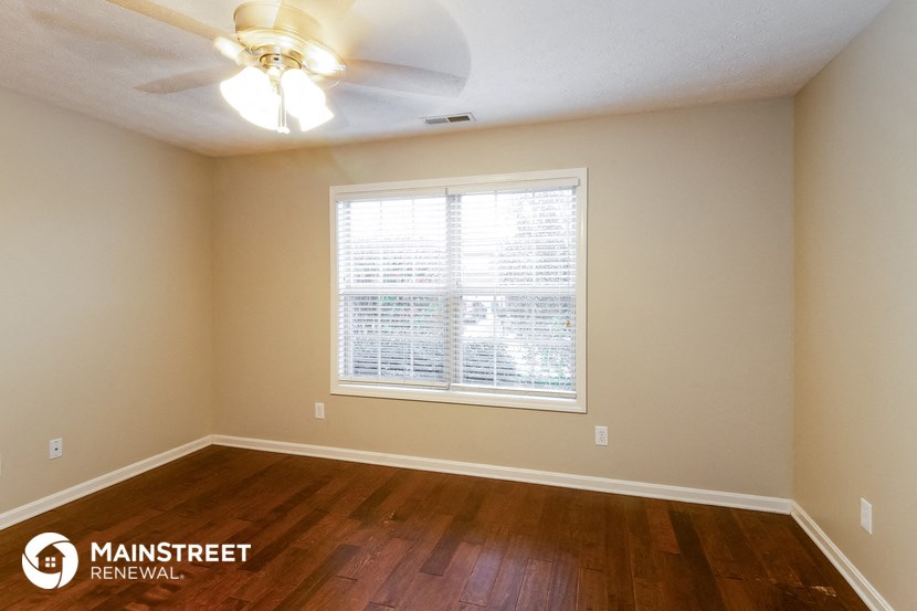 the living room of a home with wood floors and a ceiling fan