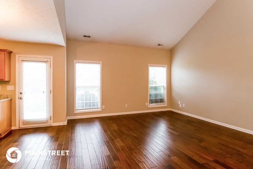 the living room of an empty house with wood floors and windows
